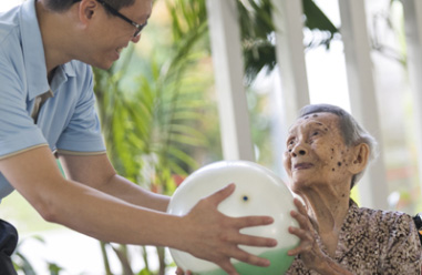 A guy passing a ball to an elderly women