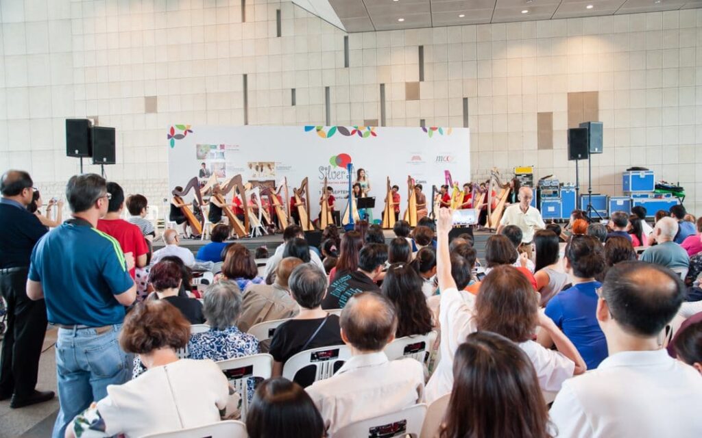 a group of people in a room with a stage and a group of people in chairs