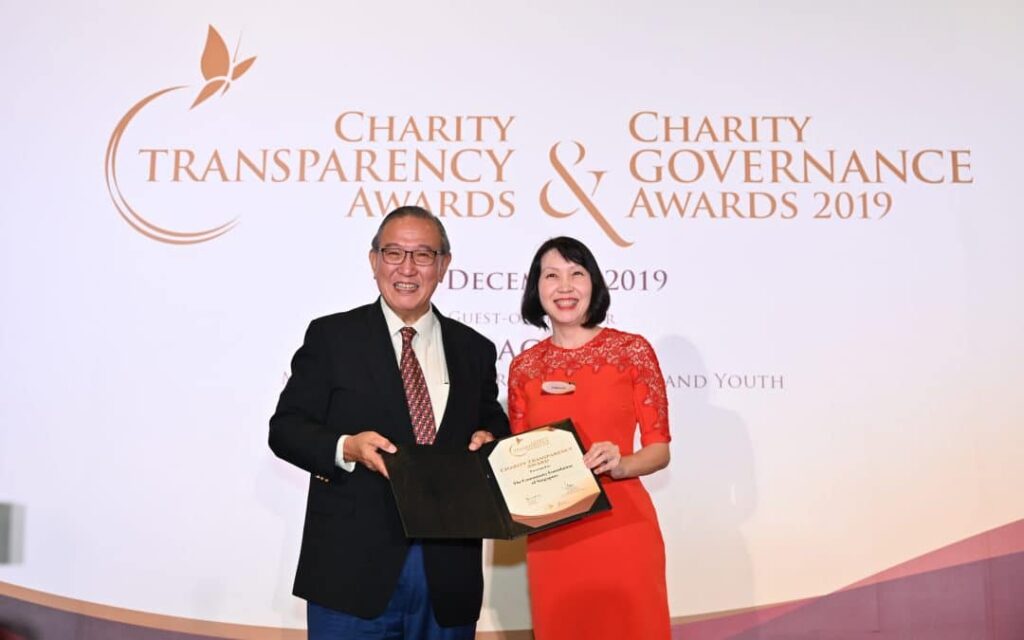 A man and woman proudly display an award at a charity transparency and governance event, symbolizing their recognition for outstanding achievements.