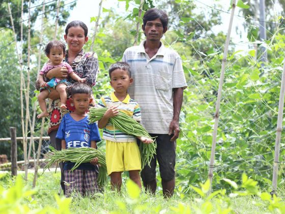 a group of people standing in a field with a bunch of vegetables